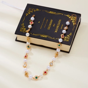 Detailed shot of floral pearl necklace with colorful crystals on a black notebook