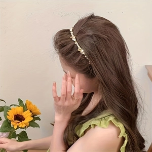 Elegant gold flower headband with pearl accents worn by a female model in profile