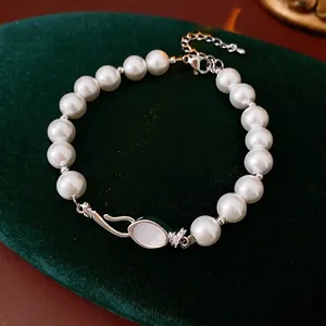 Elegant pearl bracelet with a shell centerpiece and zircon accents on a velvet cushion