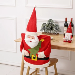 Red Santa Claus chair cover with Christmas tree decor on a wooden chair in home setting