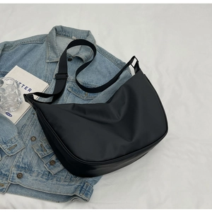 Fashionable black nylon crescent crossbody bag styled on a casual denim jacket background