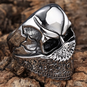Detailed macro view of skull ring with engraved mask patterns on a rustic bark background