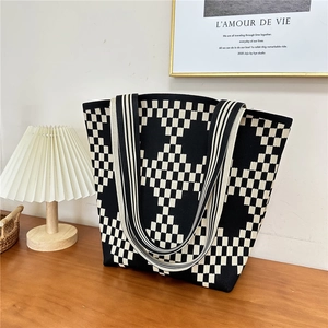 Detailed knit tote bag with black and white checkerboard pattern on a wooden table