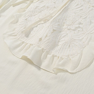 Detailed close-up of white lace embroidery and ruffled hem on cotton blend fabric