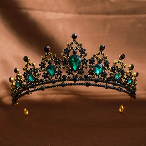 Detail of golden crown with black gems and emerald teardrop stones on brown cloth