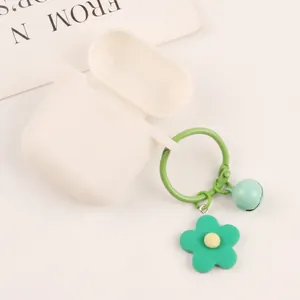 Detail of white silicone headphone case with green floral charm and small blue bell