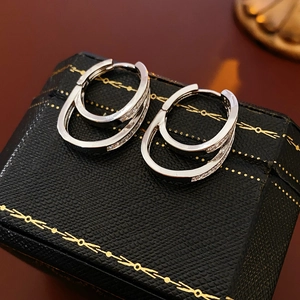 Close-up of silver double-layered crisscross earrings with cubic zirconia on jewelry box