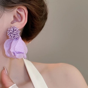 Close-up of floral drop earrings with purple beads and light translucent fabric petals
