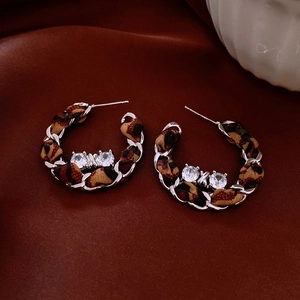 Detail of C-shaped silver chain earrings with leopard print fabric and zircon inlay