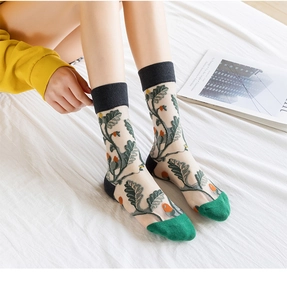 Close-up of sheer mesh socks with green leaf embroidery and orange fruit patterns