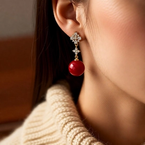 Detail of 18K gold-plated floral earrings with zircon and red round pearl drop on model