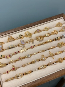 Gros plan de bagues plaquées or avec zircons et logos de marque dans un écrin