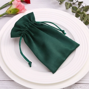 Detailed view of dark green velvet drawstring jewelry pouch on white ceramic plates