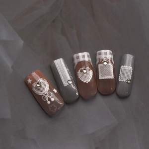 Detailed view of lace pattern and rhinestone nail art stickers on dark fabric background