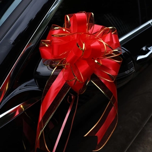 Red oversized decorative bow with gold edges on a black car rearview mirror for weddings