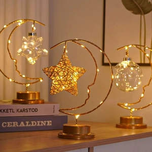 Close-up of golden moon-shaped metal table lamps with warm LED fairy lights and star ornaments