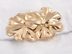 Detail of white elastic waist belt featuring a decorative large gold petal metal buckle