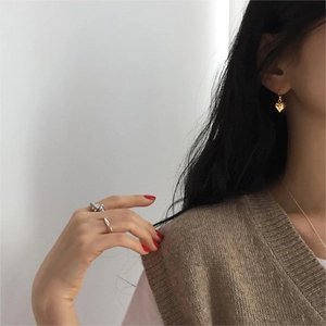 Detailed view of model wearing golden heart earrings and silver rings in French style