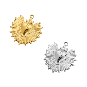Detailed view of heart-shaped pendants in gold and silver with ray texture and metal loop