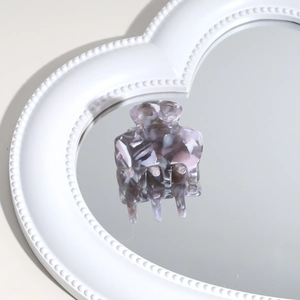 Detailed close-up of a marble texture acetate hair claw clip on a heart-shaped mirror