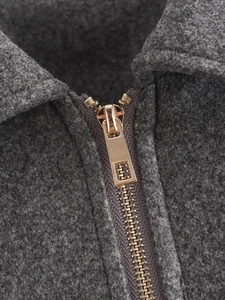 Nahaufnahme eines hochwertigen rotgoldenen Metallreißverschlusses an einer grauen Tweedjacke