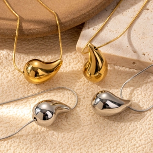 Minimalist gold and silver water drop necklaces with polished finish on stone background