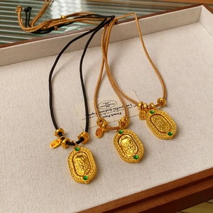 Detail of gold-plated woven necklaces featuring dragon charms and emerald gemstones