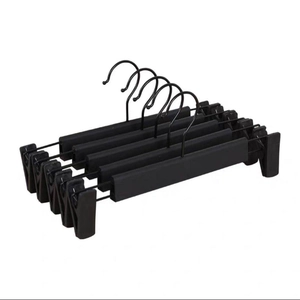 Stack of black plastic pants hangers with adjustable non-slip clips and metal hooks