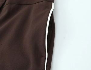 Close-up of side seam pocket and white contrast stripe on brown straight-leg trousers