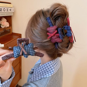 Detail of red and blue plaid hair claw clip featuring a 3D teddy bear and ribbon bow accessory