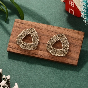 Macro view of crystal encrusted triangle earrings on wood with festive Christmas decor