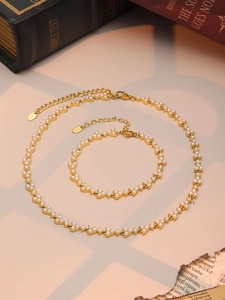 Detail of PVD gold plated stainless steel necklace and bracelet set with white pearls