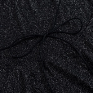 Close-up of black sequined fabric with a delicate bow tie detail and silver sparkles