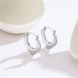 Sleek silver polished stainless steel heart shaped hoop earrings in minimalist style