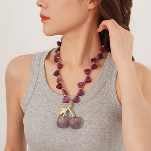 Detail of purple cherry acrylic pendant necklace with beads on woman neck