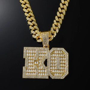 Close-up of gold Cuban chain necklace with iced-out KO letter pendant and clear crystals