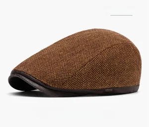 Dettaglio cappello newsboy in tweed marrone caffè con trama a spina di pesce e logo