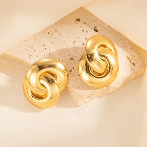 Detail of twisted double hoop gold earrings on a textured stone tray background