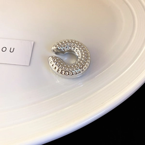 Détail macro du耳 cuff en argent en forme de C avec texture martelée sur plateau