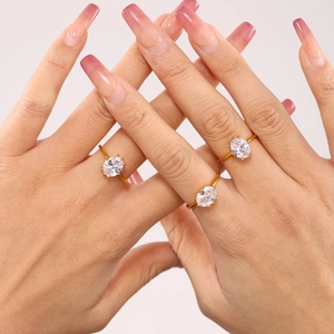 Three gold rings with oval-shaped sparkling gemstones worn by a model on clean background