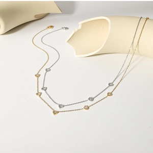 Detail of gold and silver necklaces featuring heart-shaped zircon pendants on white stone