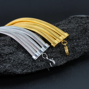 Macro shot of triple-layer gold and silver steel snake chains on black stone