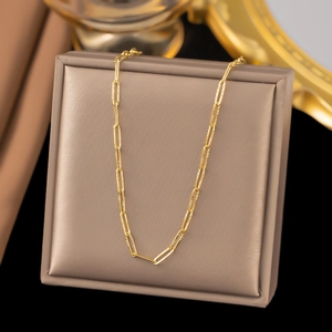 Detail of golden paperclip link chain necklace with engraved texture on champagne gift box