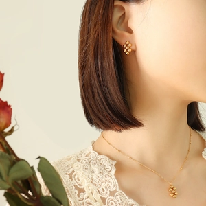 Gold geometric bead choker necklace and earrings jewelry set worn by a model
