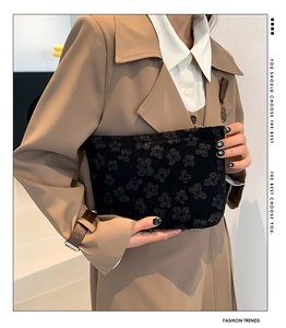 Close-up of black envelope clutch bag featuring detailed 3D floral embossed texture