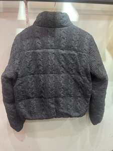 Detail view of charcoal gray cable knit texture on back of puffer jacket with stand collar