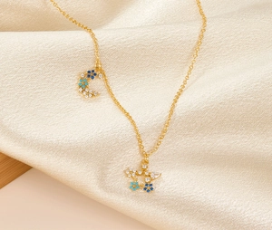 Detail of gold star and moon pendant necklace with blue zircons on satin fabric
