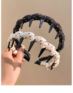 Close-up of two non-slip polka dot headbands with teeth in black and white fabric