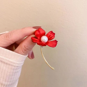 Detail of red flower brooch with gold stem, white pearl center and sparkling crystals