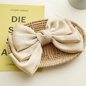 Macro shot of large triple-layered champagne satin bow hair clip on a woven basket